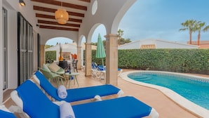 Un área junto a la piscina con sillones, una mesa y una alberca.