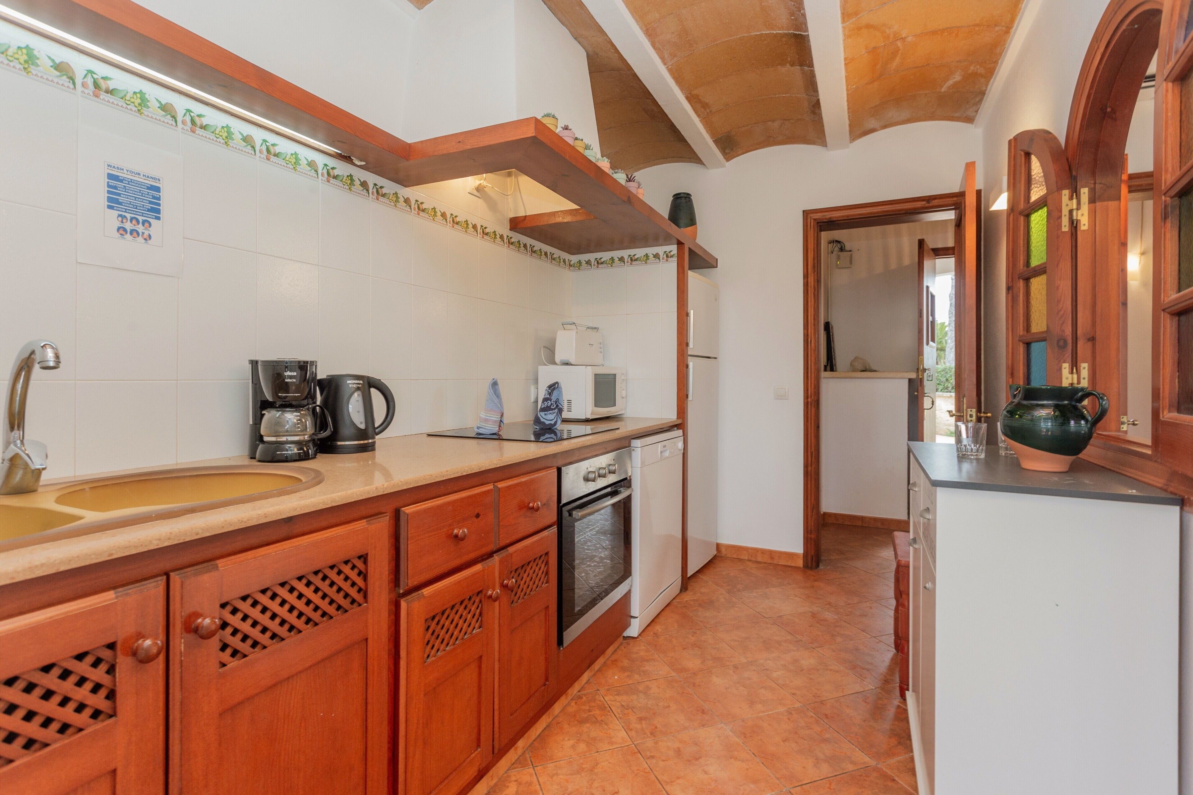 A kitchen with a sink, coffee maker, microwave, oven, and wooden cabinets.