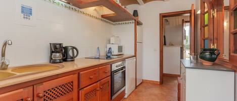 A kitchen with a sink, coffee maker, microwave, oven, and wooden cabinets.