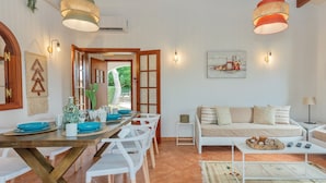 Un área de comedor con una mesa y sillas de madera, un sofá y una mesa auxiliar.