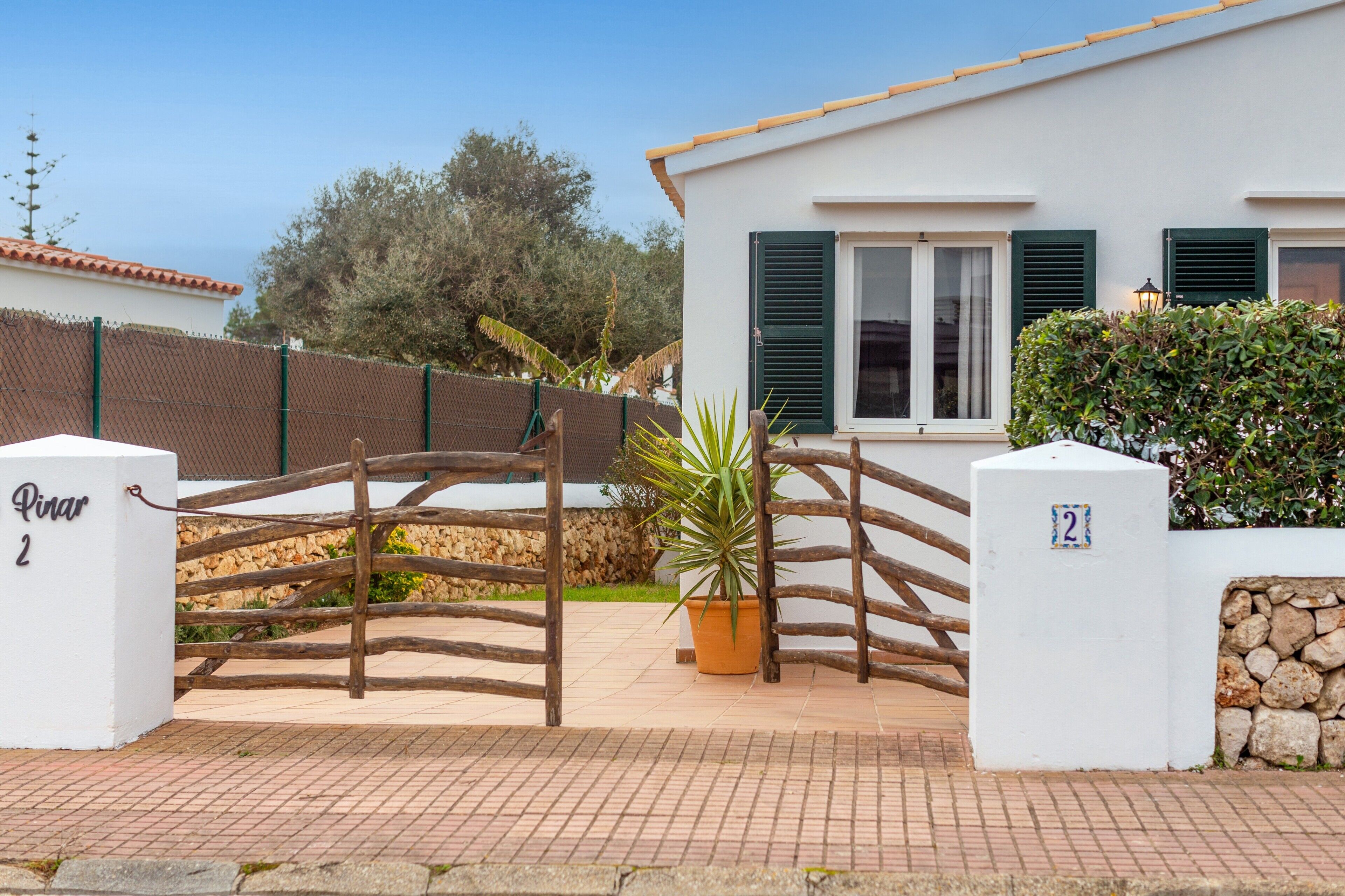 Un edificio blanco con un muro de piedra, una puerta de madera y una planta en maceta.