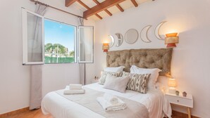Een slaapkamer met een bed, nachtkastje, raam met gordijnen en decoratie aan de muur.