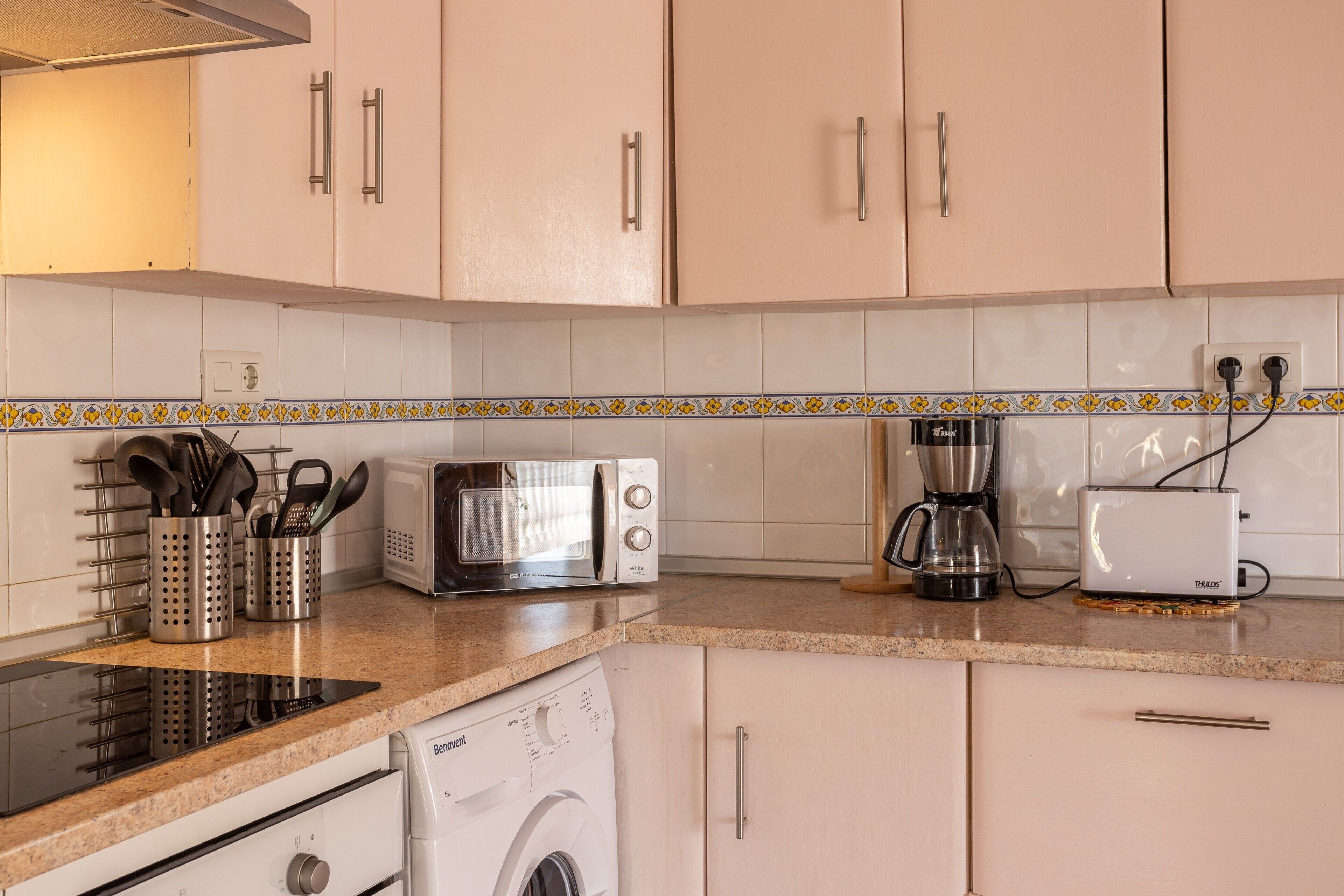 Eine Küche mit Mikrowelle, Toaster, Kaffeemaschine und Waschmaschine.