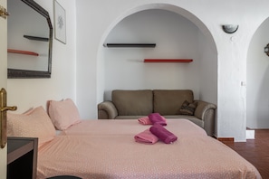 Un dormitorio con cama, sofá, espejo y estante en la pared.