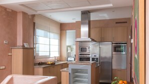 A modern kitchen with built-in appliances, a central island, and a window providing natural light. - Villa Lila with Private Pool, Garden and Wi-Fi (Benalup Casas Viejas)