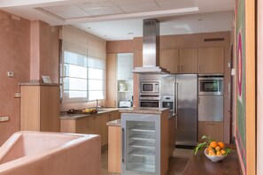 Une cuisine moderne dotée d’appareils électroménagers intégrés, d’un îlot central et d’une fenêtre laissant entrer la lumière naturelle.