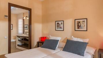 Una habitación de hotel con cama, mesita de noche, espejo y dos cuadros en la pared.