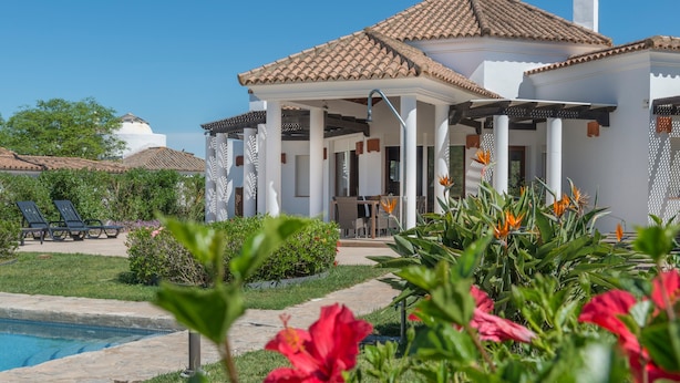 A white building with a tiled roof, a pool, and a garden with flowers. - Villa Lila with Private Pool, Garden and Wi-Fi (Benalup Casas Viejas)