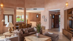 A spacious living area with a high ceiling, a sofa, a coffee table, and a television. - Villa Lila with Private Pool, Garden and Wi-Fi (Benalup Casas Viejas)