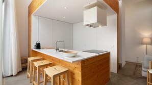 Een moderne keuken met een houten keukeneiland, barstoelen, een spoelbak en een ingebouwde kookplaat.