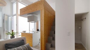 Een moderne woonkamer met een bank, een trap en een keukenhoek.