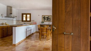 A kitchen with a wooden island, white cabinets, a tiled floor, and a dining area with a wooden table and chairs. - House with Private Pool, Mountain Views, and Wi-Fi in Begur (Begur)