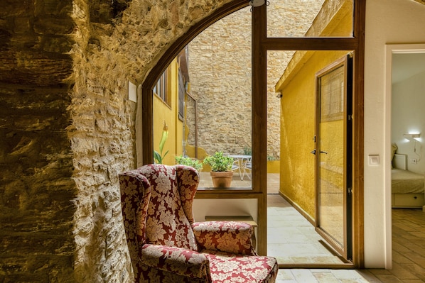 A stone wall, a chair, a potted plant, and a door leading to an outdoor area.