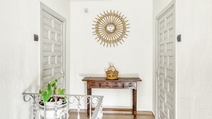 A hallway with white walls, a wooden console table with a basket, and a decorative wall piece. - Apartment 'Residencial  2º 2ª' with Shared Terrace, Balcony and Wi-Fi (Begur)
