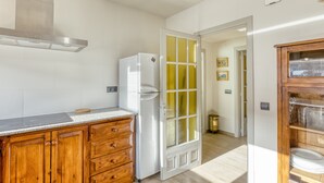 A kitchen with wooden cabinets, a stainless steel range hood, and a white refrigerator. - Apartment 'Residencial  2º 2ª' with Shared Terrace, Balcony and Wi-Fi (Begur)