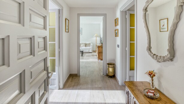 A hallway with a white door, a mirror, and a vase with flowers on a wooden console. - Apartment 'Residencial  2º 2ª' with Shared Terrace, Balcony and Wi-Fi (Begur)