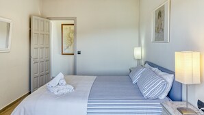 A hotel room with a bed, a bedside lamp, a door, and a framed picture on the wall. - Apartment 'Residencial  2º 2ª' with Shared Terrace, Balcony and Wi-Fi (Begur)
