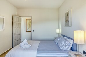 Une chambre d’hôtel avec un lit, une lampe de chevet, une porte et un tableau encadré au mur.
