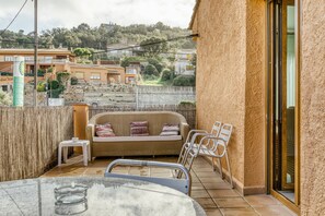 Un balcon avec un canapé, des chaises, une petite table et un verre.