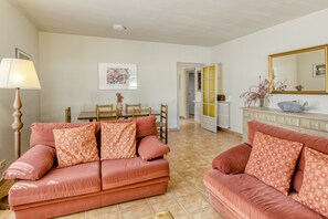 A living room with two sofas, a dining table, and a mirror.