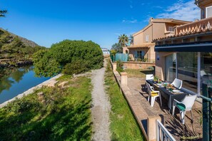 A riverside path leading to a building with outdoor seating and a view of the water.