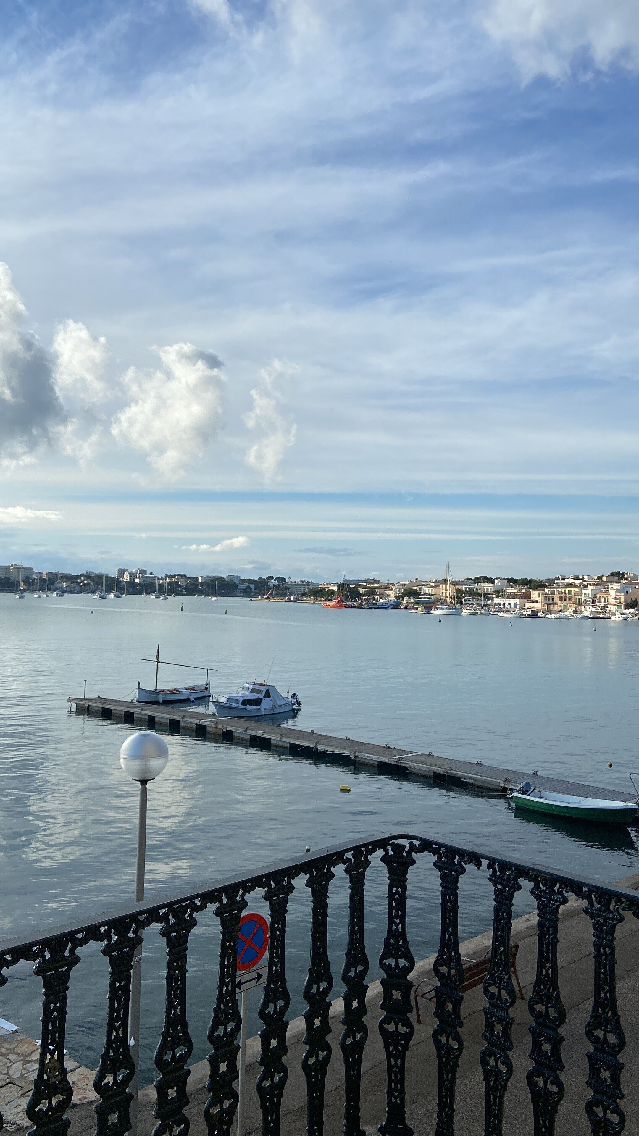 A waterfront view with boats docked, a pier, and a cityscape in the background.