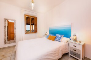 Une chambre à coucher avec un lit, une table de chevet, une lampe, un tableau et un miroir.