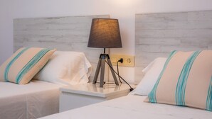 Une chambre d’hôtel avec deux lits, une table de chevet, une lampe et une prise électrique.