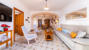 Un salon avec un canapé, des fauteuils, une table basse et un téléviseur.