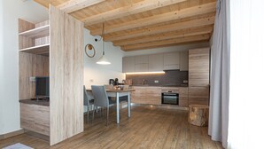 A modern kitchen with wooden cabinets, a dining area with a table and chairs, and a visible oven. - Apartment 'Sant'Antoni Plan' with Mountain View, Shared Terrace and Wi-Fi (Livigno)