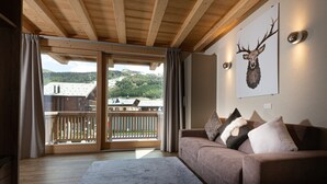 A wooden ceiling, a brown sofa with cushions, a large rug, and a deer head artwork on the wall. - Apartment 'Sant'Antoni Plan' with Mountain View, Shared Terrace and Wi-Fi (Livigno)