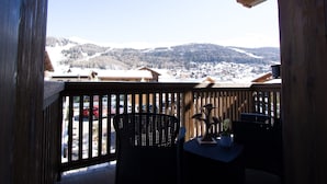 A wooden balcony with wicker furniture, overlooking a snowy mountain town. - Apartment 'Sant'Antoni Fontana' with Mountain View, Shared Terrace and Wi-Fi (Livigno)