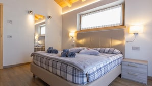 A bedroom with a bed, a nightstand, a window with blinds, and a wooden ceiling. - Apartment 'Sant'Antoni Fontana' with Mountain View, Shared Terrace and Wi-Fi (Livigno)