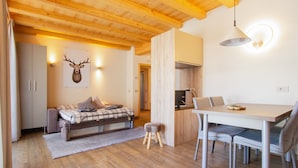A cozy room with a bed, a dining table, and a kitchen area. - Apartment 'Sant'Antoni Fontana' with Mountain View, Shared Terrace and Wi-Fi (Livigno)