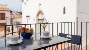 Ein Balkon mit einem Tisch für zwei Personen, einer Obstschale und einer Tasse.