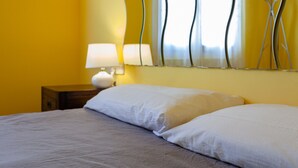 Ein Bett mit weißer Bettwäsche, ein Nachttisch mit Lampe und eine Wand mit Wellenmuster.