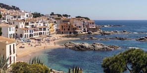 A coastal town with buildings, a beach, and rocky coastline.