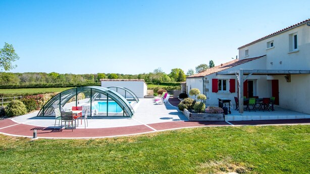 Ett hus med en swimmingpool, utomhusmöbler och en trädgård.