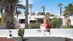 A modern building with a courtyard, palm trees, and a cactus.