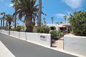 Un hôtel aux murs blancs, agrémenté de palmiers, doté d’un patio et surplombant un ciel d’un bleu limpide.