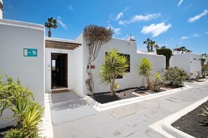 Un bâtiment blanc avec un palmier, une porte et un petit jardin.
