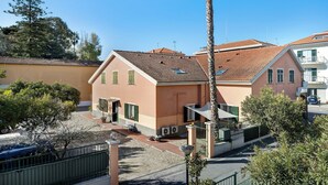 A residential building with a tiled roof, a balcony, and a small garden area.