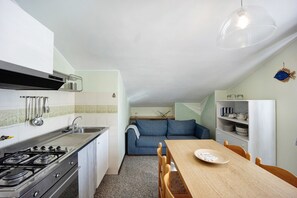 Una cucina funzionale con piano cottura, lavello e zona pranzo con sedie e tavolo.