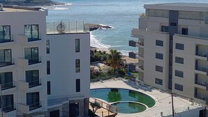 Un hôtel en bord de mer à l’architecture moderne, doté de balcons, d’une piscine et offrant une vue sur la mer.