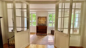 A room with a wooden floor, a wooden cabinet, and a large window with a view of greenery.