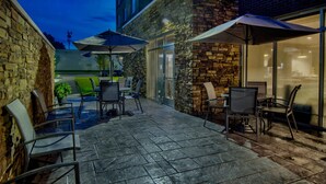 An outdoor patio area with stone walls, outdoor seating, and umbrellas. - Fairfield by Marriott Inn & Suites Rochester Hills (Rochester)