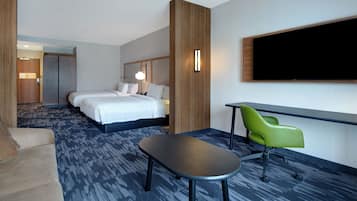 Una habitación de hotel con una cama, un escritorio, una silla verde y un televisor de pantalla plana.