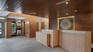 A reception area with wooden paneling, a reception desk, and a wall-mounted decorative piece. - Fairfield by Marriott Inn & Suites Rochester Hills (Rochester)