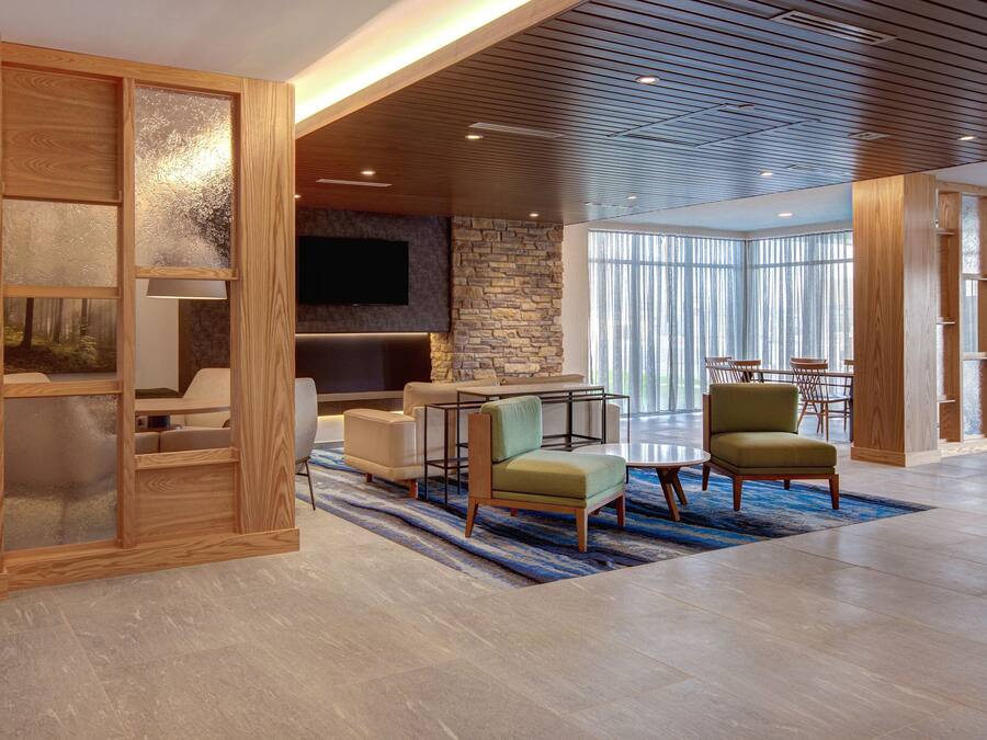 A spacious lobby with a modern design, featuring a stone accent wall, a flat-screen TV, and a seating area with sofas and chairs.
