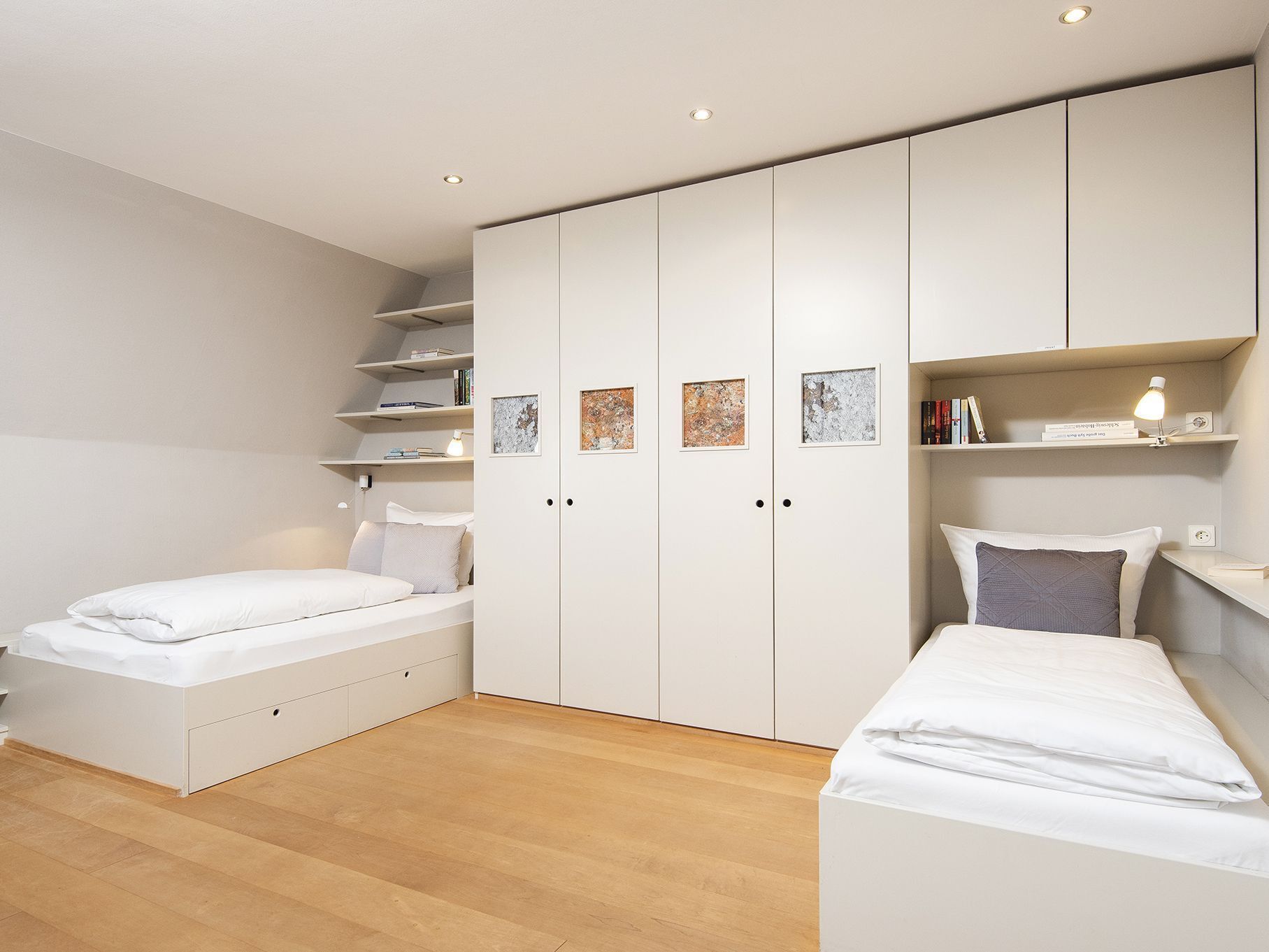 A modern bedroom with a bed, a desk, and built-in storage.